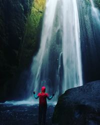 Rear view of man standing against waterfall