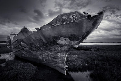 Abandoned boat moored on beach against sky