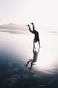 Full length of silhouette person on beach against sky during sunset