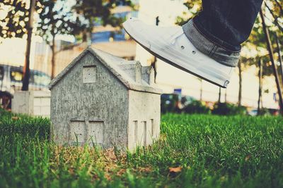 Cropped image of leg stepping on house model in yard