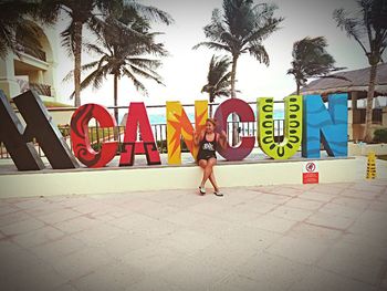 Woman by palm trees against sky