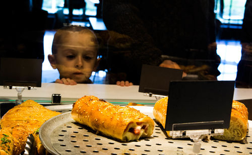 Boy looking at food with label on tray in display cabinet