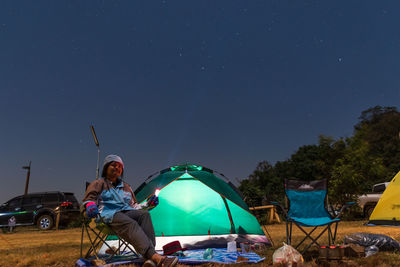 People sitting at tent against clear sky at night