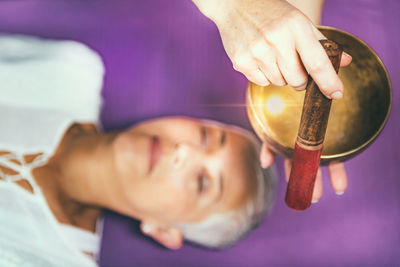 Cropped hands of woman playing singing bowl for customer in spa