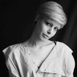 Portrait of beautiful woman with short hair standing against black background