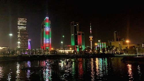 Illuminated modern buildings in city against sky at night