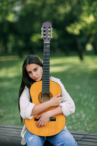 An attractive girl with a guitar in the park. the concept of creative hobbies 