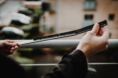 Cropped hands of cleaner holding blade outdoors