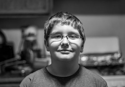 Close-up portrait of boy wearing eyeglasses standing in kitchen