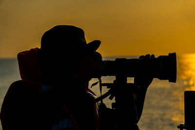 Portrait of silhouette man photographing against sky during sunset