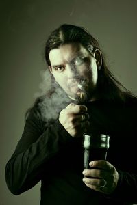 Portrait of man smoking against gray background