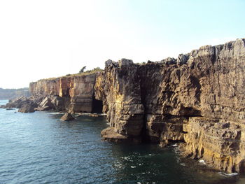 Scenic view of sea and cliff against clear sky