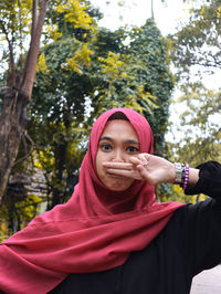 Portrait of senior woman standing against pink trees