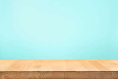 Close-up of wooden table against blue wall