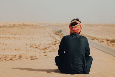 Rear view of man on sand at beach against sky