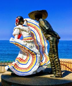 Statue by sea against clear blue sky