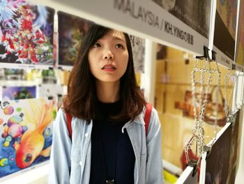 Close-up of young woman standing against store