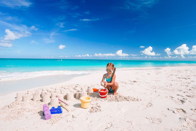 Woman sitting on beach by sea against sky