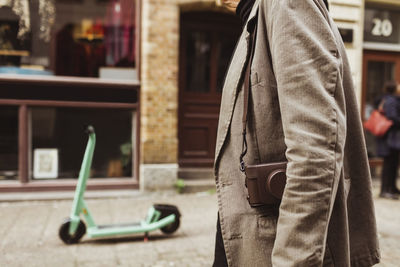 Midsection of senior man with camera walking on street