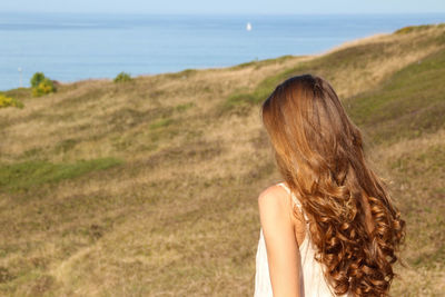 Close up portrait of a young girl with long, shiny and healthy wavy brown hair in a field 