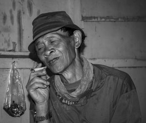 Portrait of man holding camera against wall