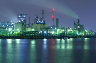 Illuminated factory against sky at night