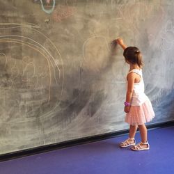 Full length of girl drawing on blackboard