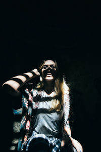 Young woman wearing mask against black background