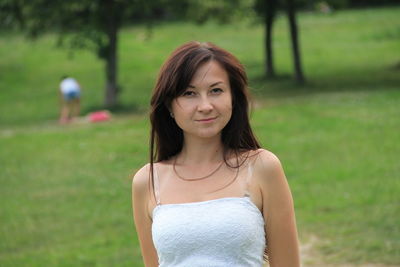 Portrait of young woman smiling while standing at park