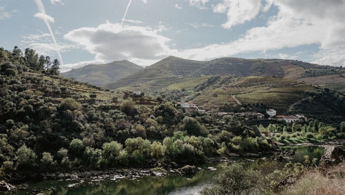Scenic view of river by mountains against sky