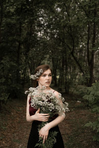 Young woman standing by tree in forest