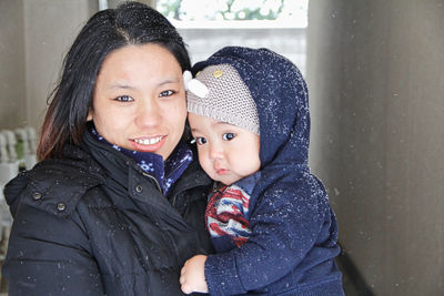 Portrait of happy mother holding toddler during winter