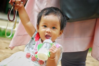 Portrait of cute baby girl holding milk bottle