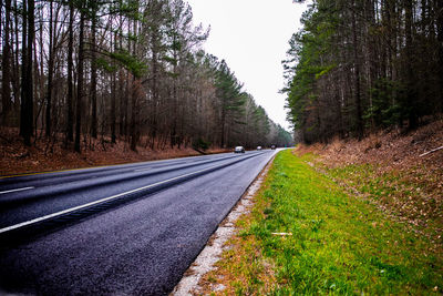 Road amidst trees in forest against sky