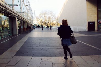 Rear view of woman walking on cobblestone street