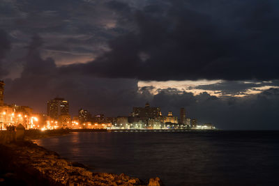 City at waterfront against cloudy sky