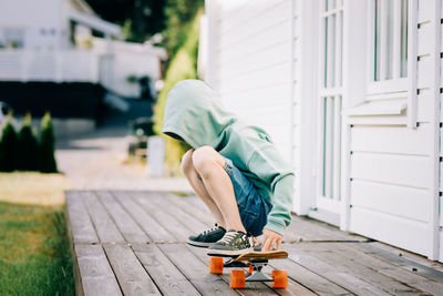 Boy sat on a skateboard with his hood up hiding his face