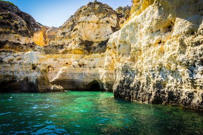 Rocks in sea against mountain
