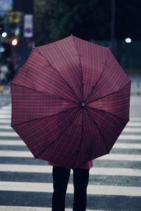 Rear view of woman with umbrella walking on street