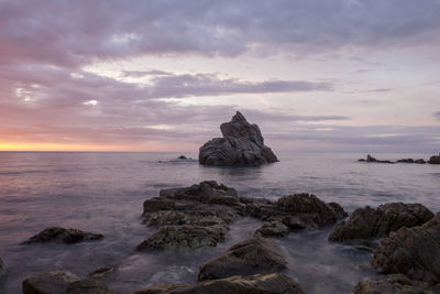 Rocks on sea against sky during sunset