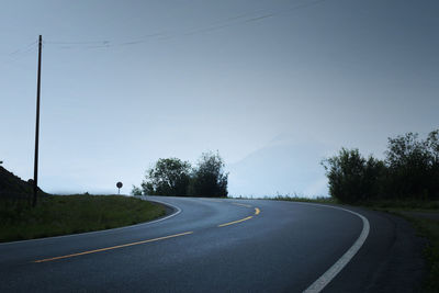 Empty road amidst trees against sky