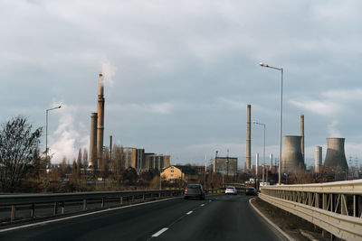 Cars on road by city against sky