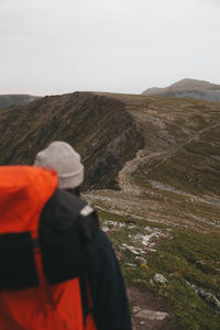 Rear view of man standing on mountain against sky