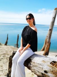 Woman sitting on wood at beach