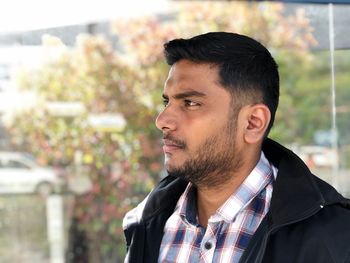 Close-up of man looking away against trees