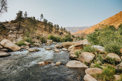 Stream flowing through rocks against sky