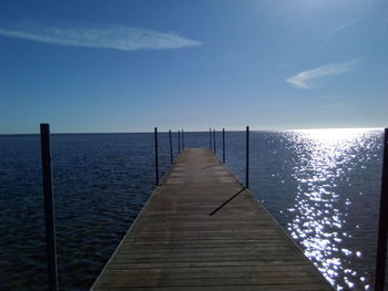 Wooden pier over sea against blue sky