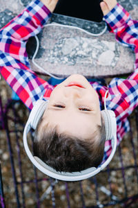 Cute boy listening music while using mobile phone outdoors