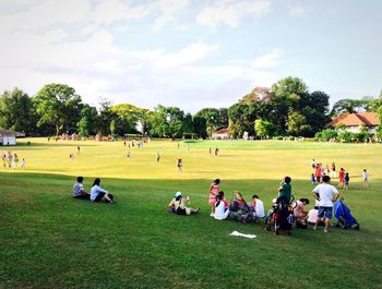 People relaxing on grassy field in park