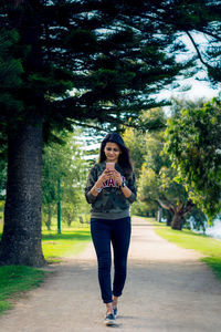 Young woman using mobile phone while walking in park